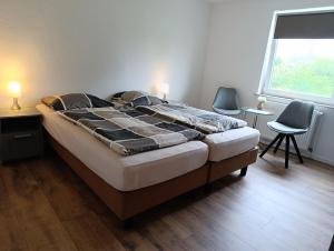 a bed in a room with two chairs and a window at Landhaus Leopold in Sanitz