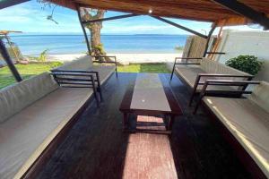 a porch with benches and a table and the beach at Angelito's Beach House Siargao near Beach in General Luna
