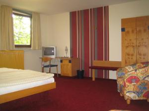 a hotel room with a bed and a television at Hotel & Apartmenthaus Zum Pfingsttor in Friedrichswald