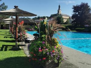 a resort with a swimming pool with flowers and an umbrella at Boutique Hotel Toso Genussreich in Leutschach