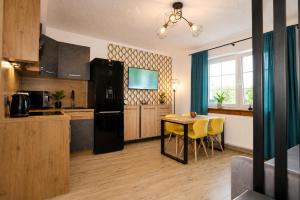 a kitchen with a table and a black refrigerator at Ewilla- apartamenty Wojcieszyce in Wojcieszyce
