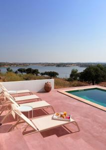 a patio with two chairs and a swimming pool at Monte dos Alpendres I Farmhouse in Serpa +41 photos