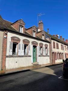 an old brick building with a green door on a street at Chez Merlin le brocanteur in Charny