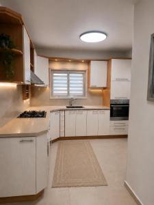 a kitchen with white cabinets and a sink and a window at וילה נחל טביה in Arad