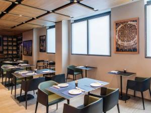 a dining room with tables and chairs and windows at Novotel Parma Centro in Parma +183 photos