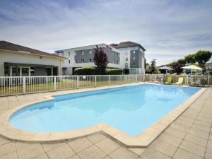 a large blue swimming pool with a fence at ibis budget Cahors in Cahors