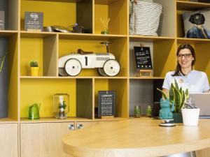 a woman sitting at a counter in a coffee shop at Aparthotel Adagio access Montpellier Centre in Montpellier