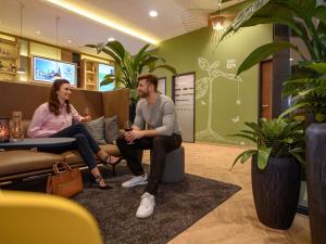 a man and a woman sitting in a waiting room at Ibis Styles Aschaffenburg in Aschaffenburg