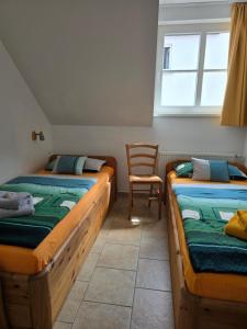 two beds in a room with a chair and a window at Ferienresidenz Am Strom in Warnemünde
