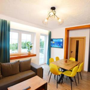 a living room with a couch and a table and chairs at Ewilla- apartamenty Wojcieszyce in Wojcieszyce