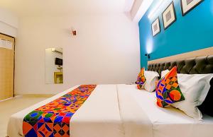 a bedroom with a large white bed with colorful pillows at Hotel Goldwind stay - Near Karkardooma Metro in New Delhi +21 photos
