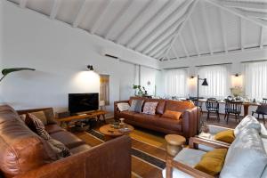 a living room with brown leather furniture and a table at Abacatus Farmhouse in Tavira