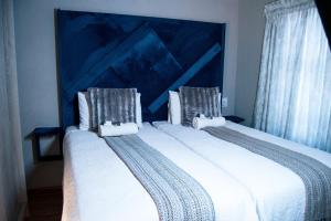 a bedroom with two beds with white sheets and a blue headboard at Dam View Guest house in Bokong