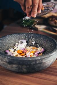 a person is sprinkling spices on a bowl of food at Hotel Goldwind stay - Near Karkardooma Metro in New Delhi