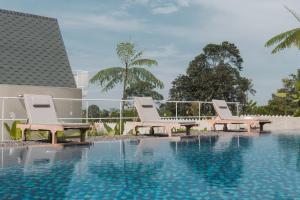 two white chairs sitting next to a swimming pool at Suka Village 