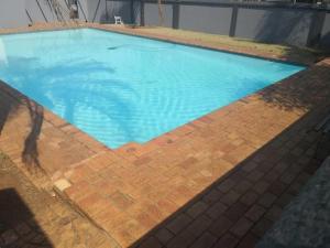 a large blue swimming pool with a brick floor at Place At Menlyn in Pretoria