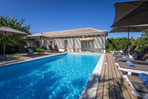 a swimming pool with chairs and umbrellas at Abacatus Farmhouse in Tavira