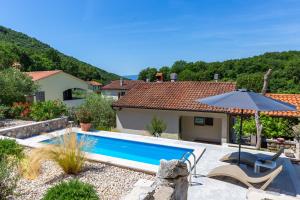 a house with a swimming pool and an umbrella at Holiday House - Old Olive in Porozina