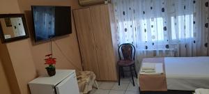 a room with a bed and a chair and a television at Къща за гости "Чекичев" in Svilengrad