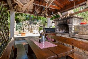 an outdoor patio with a wooden table and a fireplace at Holiday House - Old Olive in Porozina