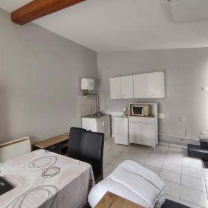 a room with a kitchen with a table and a microwave at L’Adresse 262 