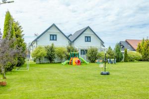 a house with a yard with a playground at Domki Kalipso in Sarbinowo