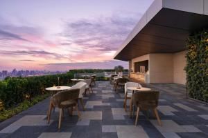 a rooftop patio with tables and chairs at sunset at AC Hotel by Marriott Manila in Manila