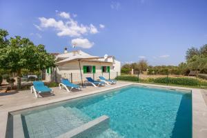 a swimming pool with blue chairs and a house at Sa Vinya d'Es Trenc in Campos
