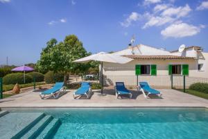 a pool with chairs and an umbrella and a house at Sa Vinya d'Es Trenc in Campos