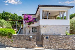 a house with a stone wall and purple flowers at Holiday House - Old Olive in Porozina