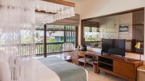 a bedroom with a bed and a desk with a television at Kayaam Wellness in Tangalle