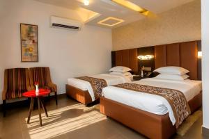 a hotel room with two beds and a red table at D'more Dhaka Hotel & Resort in Dhaka