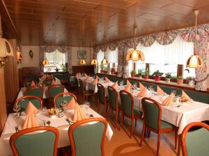 a dining room with tables and chairs in a restaurant at Hotel & Apartmenthaus Zum Pfingsttor in Friedrichswald