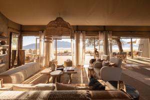 a living room with a couch and chairs and windows at Wolwedans Dune Camp in NamibRand