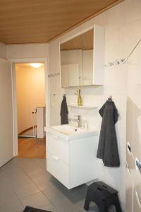 a white bathroom with a sink and a mirror at Haus Figaro mit Hund in Wangerland +26 photos