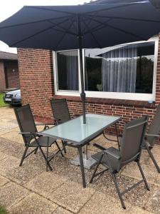a glass table with two chairs and an umbrella at Haus Horst in Schillig