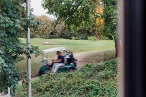 a man riding a golf cart down a golf course at Les Terrasses de Durbuy in Durbuy