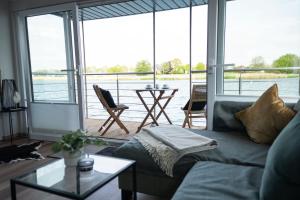 a living room with a couch and a view of the water at Hausboot Kajüte am Nixensteg Am Wangermeer mit Hund in Wangerland