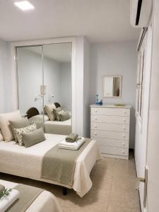 a bedroom with two beds and a dresser and a mirror at Albaricoques Sun & Beach in Maspalomas