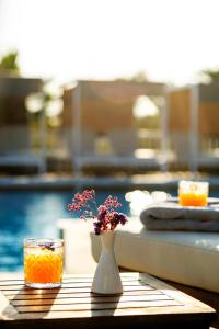 a vase with flowers sitting on a table next to a pool at San Marco Hotel and Villas in Houlakia