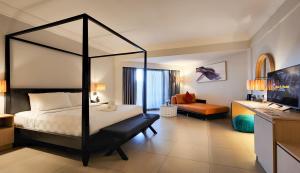 a bedroom with a canopy bed and a living room at Sand & Sandals Desaru Beach Resort & Spa in Desaru +49 photos