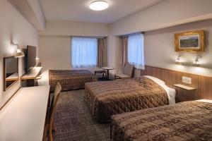 a hotel room with two beds and a table at Hotel New Green Plaza in Nagaoka +12 photos