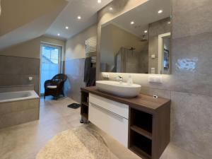 a bathroom with a sink and a tub and a mirror at Haus Strandhafer in Wangerland +40 photos