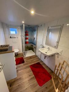 a bathroom with a sink and a red rug at Hausboot Optima in Wangerland