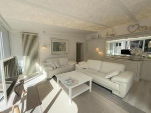 a living room with two white couches and a table at Meer Weiss in Wangerland