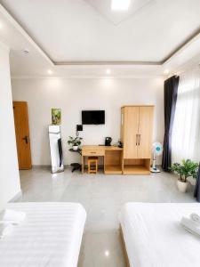 a room with two beds and a desk and a television at Thanh Nhã House in Da Lat