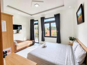 a bedroom with a bed and a couch and a tv at Thanh Nhã House in Da Lat