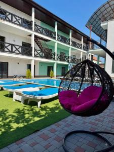 a swing in front of a building with a pool at Qzone 2 in Chornomorsk