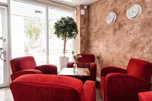a waiting room with red chairs and a table and clocks at Hotel Kalliohovi - ilmastoidut huoneet - in Rauma