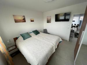 a bedroom with a bed with white sheets and green pillows at Wangeroase in Wangerland
